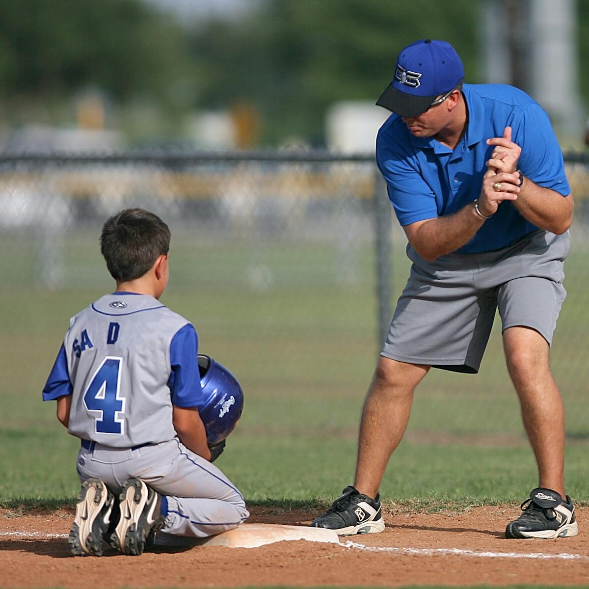 A young baseball player receives guidance from a coach during practice.